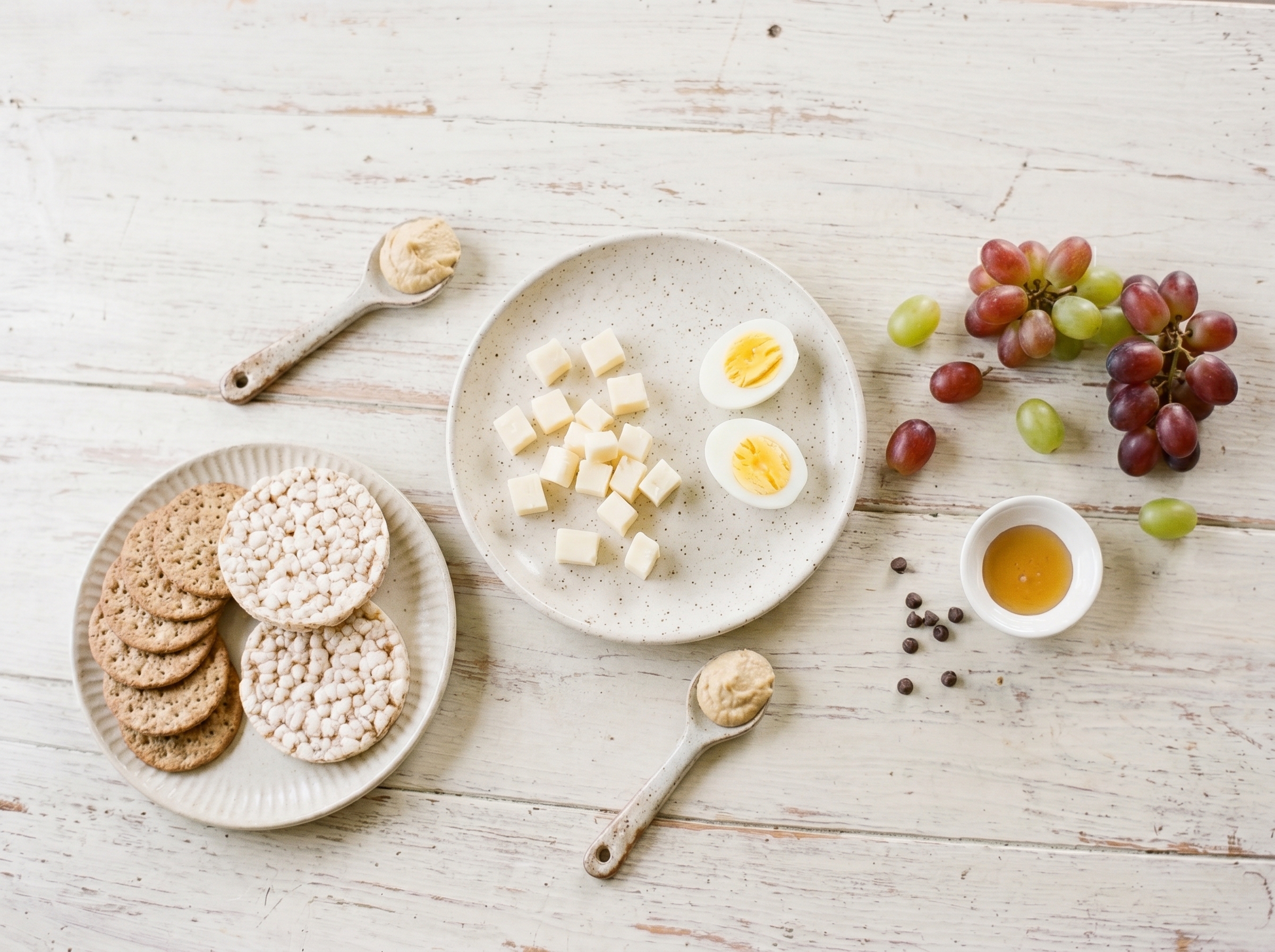 Flatlay arrangement showing crackers, cheese cubes, grapes, and small fun toppings like chocolate chips and honey drizzle