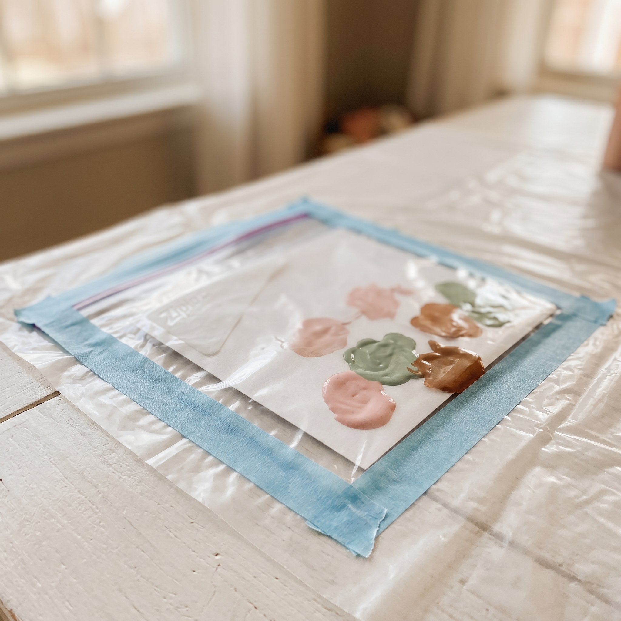 Sealed gallon ziplock bag with white cardstock inside, painter's tape securing the edges, ready for toddler painting